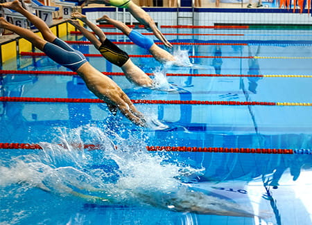 Atletas a mergulhar para a piscina, no início da prova. Mental Coaching para atletas de natação